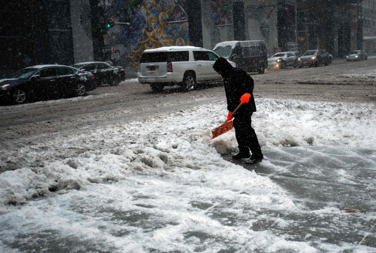 Image: A man shovels snow from a street during a winter storm in New York