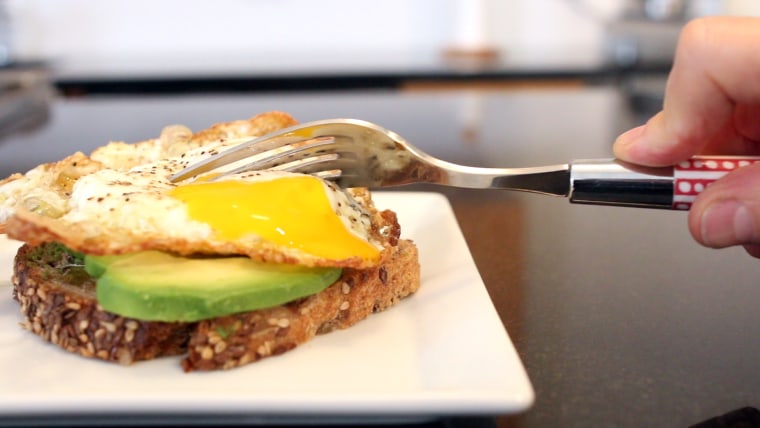 Cutting into a fried egg with a fork