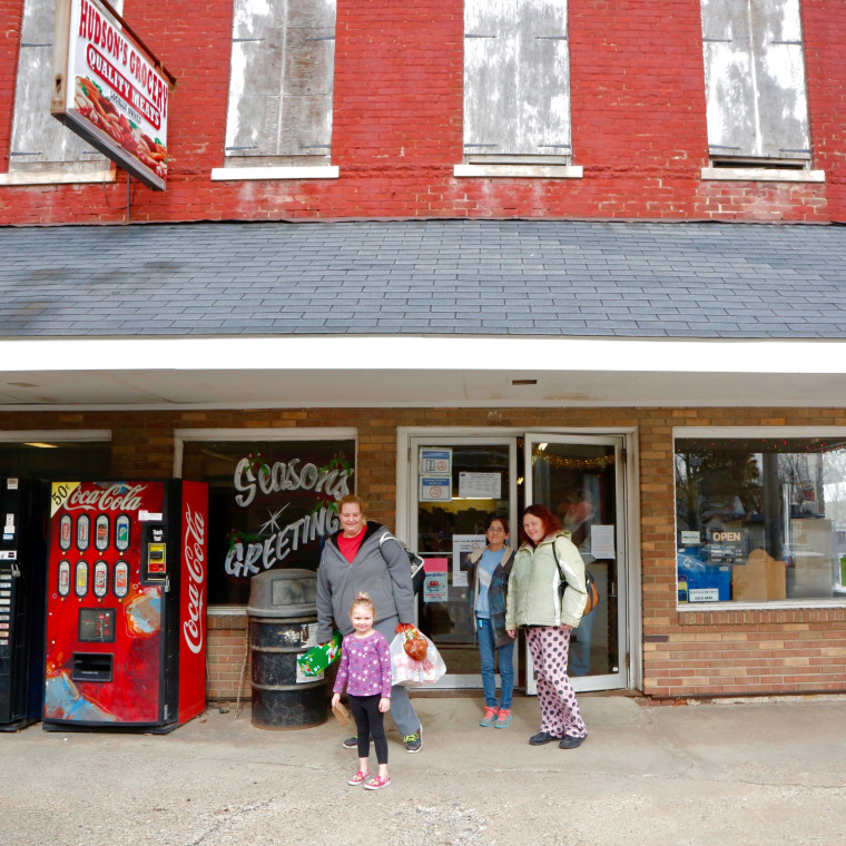 Image: Shoppers in Wayntown, Indiana, leave the town's only grocery store, Hudson's Grocery, while President Trump engages with reporters at a press conference in Washington, D.C., last week.