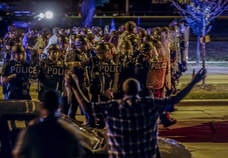 Police move in on a group of protesters throwing rocks at them in Milwaukee, Sunday, Aug. 14, 2016. The police shooting of a black man spurred two nights of violence in Milwaukee.