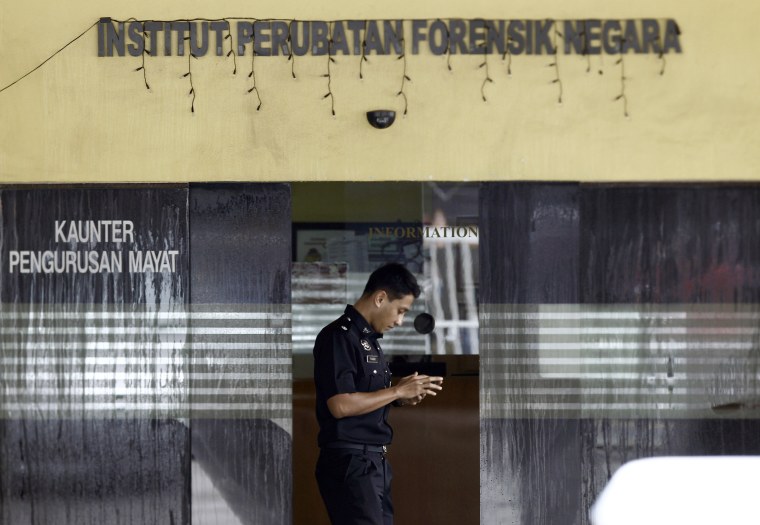 Image: A police officer checks his phone inside the forensic department at Kuala Lumpur Hospital