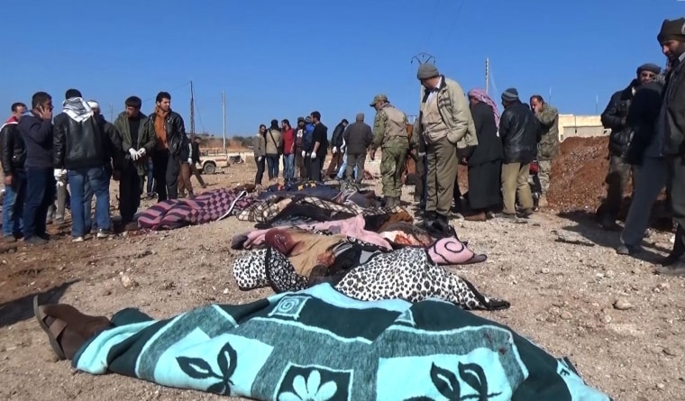 Image: Bodies wrapped in blankets lie on the ground after a bomber blew up a vehicle packed with explosives just outside the Syrian border town of al-Bab