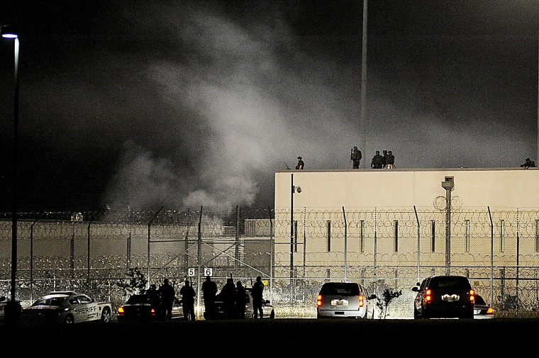 Image: Officers stand on the roof of and outside the gates at the Adams County Correctional Center in Natchez, Miss., during an inmate disturbance at the prison, May 20, 2012.