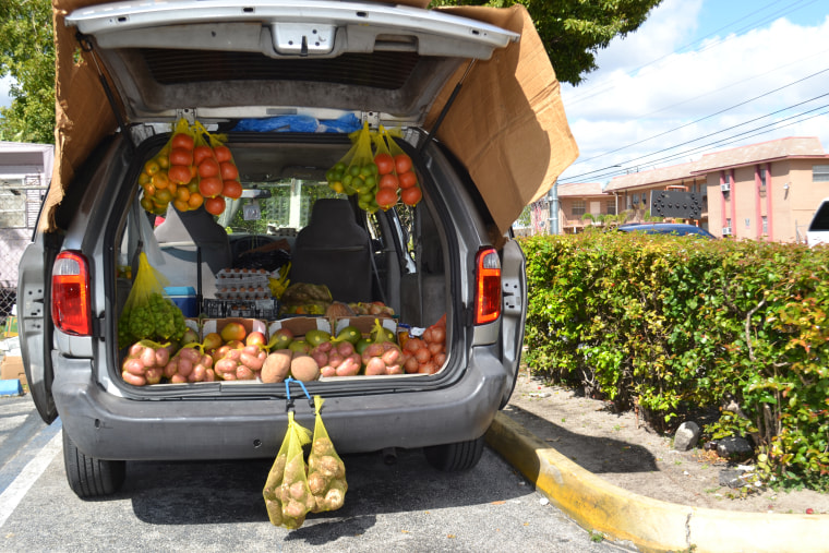 A vendor sells fruits and vegetables from the trunk of a van in the parking lot of a strip mall in Hialeah.