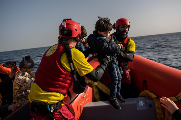 Image: A child is helped from a wooden boat