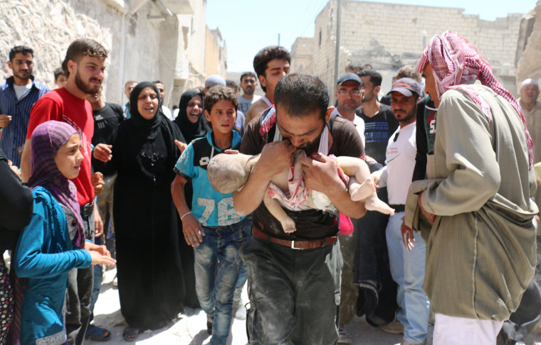 Image: A Syrian man holds the body of his child 