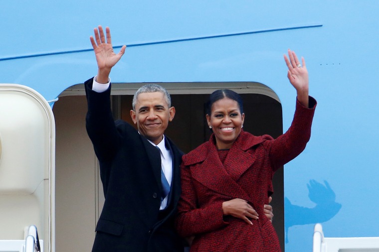 Former president Barack Obama waves with his wife Michelle as they board Special Air Mission 28000, a Boeing 747 which serves as Air Force One, at Joint Base Andrews