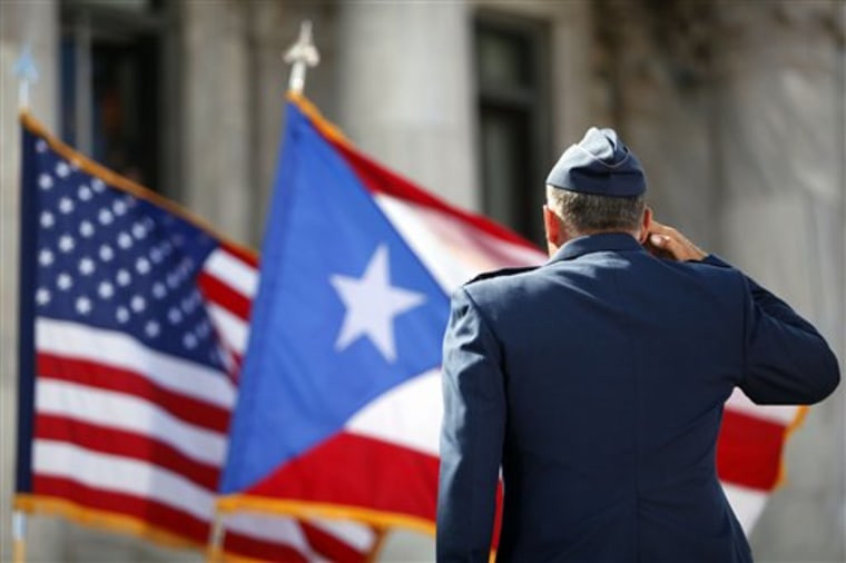 A member of the U.S. Army Honor Guard salutes the Puerto Rican and U.S. flags during the inaugural ceremony for governor-elect Alejandro Garcia Padilla, at the Capitol building in San Juan, Puerto Rico, Wednesday, Jan. 2, 2013.