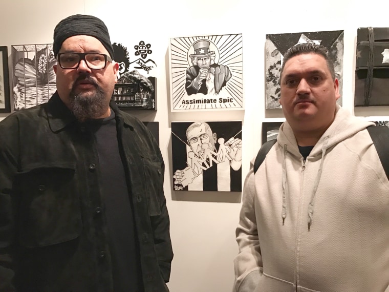 Artists Jo-El Lopez (left) and Nelson Host Santiago (right) stand next to their own work.