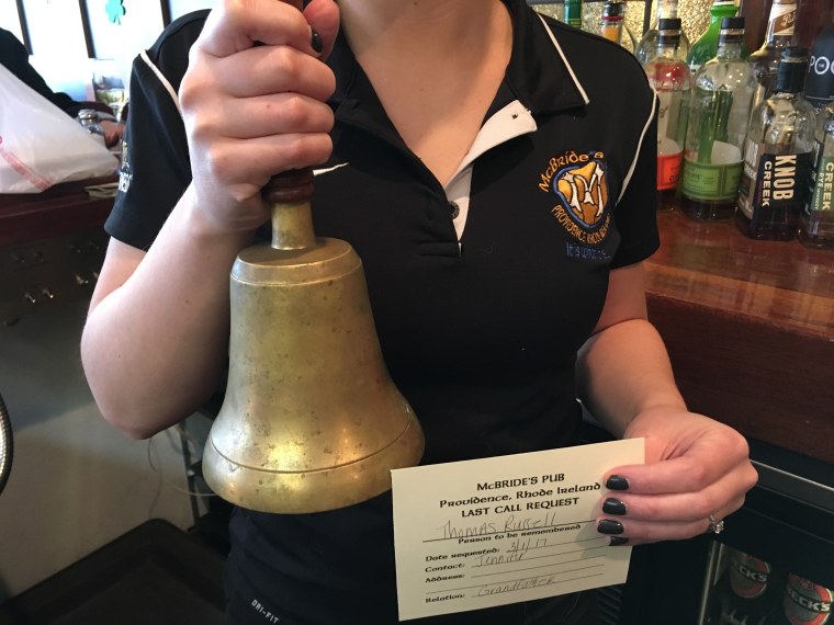 An employee of McBride's Pub in Providence, Rhode Island, holds the bell that the pub rings each night at 10 o'clock for their "Last Call" memorial tradition. Anyone can request that the bell be rung in honor of a loved one who is died, and all the patrons of the bar raise a glass in remembrance when the bell is rung. That person's name is then entered into a memorial book in the pub.