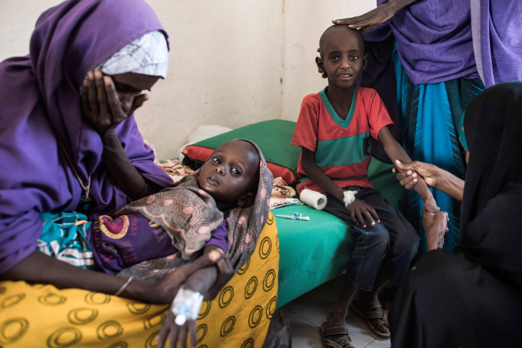 Image: Abdullahi Mohamud, 5, cries next to his mother Sahro Mohamed Mumin, 30, and brother, Abdulrahman Mahamud, 2, as a nurse struggles to find a vein for an injection at a government run health clinic in Shada, Somalia.