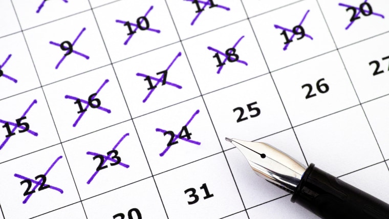 Fountain pen lying on calendar with marking days