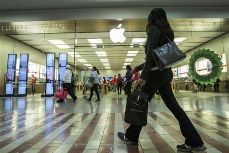 People walk past the Apple Store while shopping at the Los Cerreitos Center mall on Black Friday in Cerritos