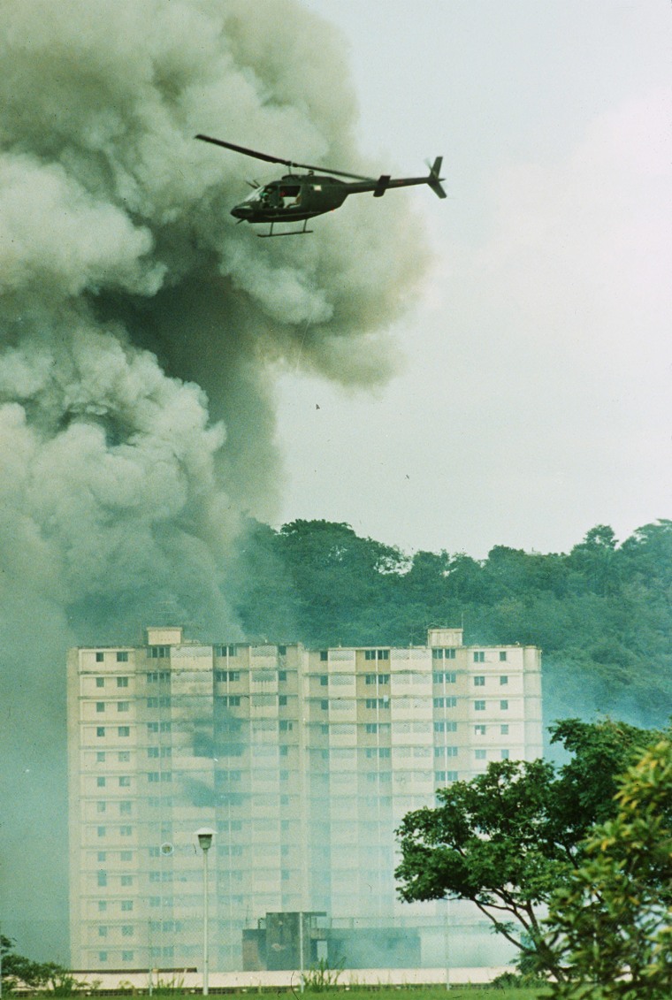 Image: A U.S. military helicopter flies over a burning building near the Pacific Defense Headquarters in Panama City on December 20, 1989