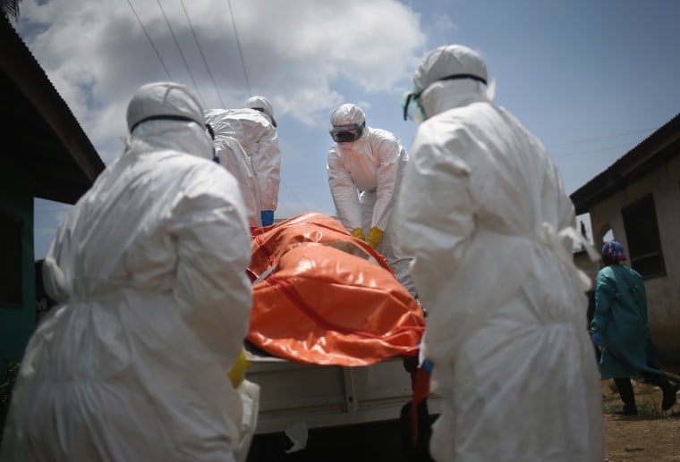 Image: An Ebola burial team loads the body of a woman, 54, onto a truck for cremation