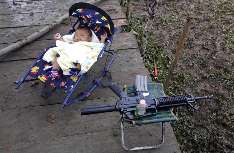 Image: 3-month-old Junior Alexis Patino, son of FARC rebel Deisy Garcia, sleeps next to his mother's weapon at a rebel camp