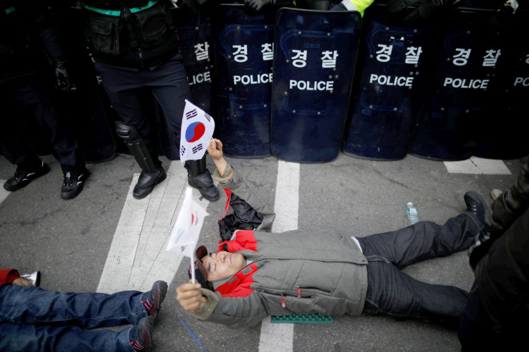 Image: A supporter of the former president lies in front of a barricade of riot police during a protest after Park's impeachment was accepted.