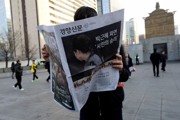 Image: A South Korean man reads an extra edition newspaper reporting on the impeachment of President Park Geun-hye.