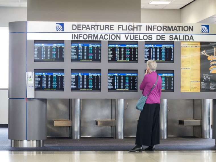 Image: Bilingual Departure Flight Information Board and Passenger, Newark Liberty International Airport, Newark, New Jersey, USA. Image shot 2012.