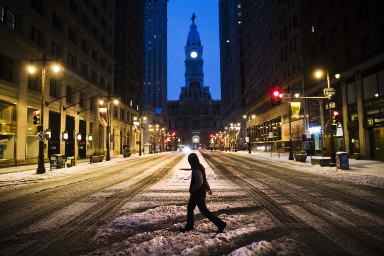 Image: A man crosses South Broad Street in view of City Hall during a winter storm in Philadelphia