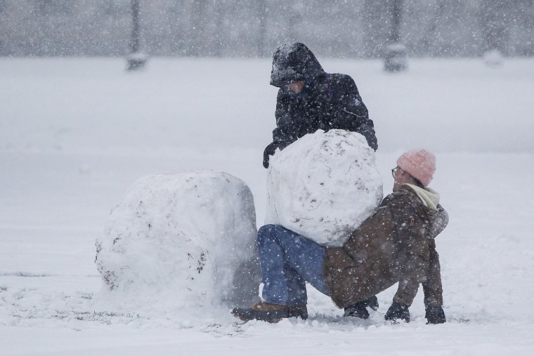 Image: Two people work to build a snowman on the Boston Common