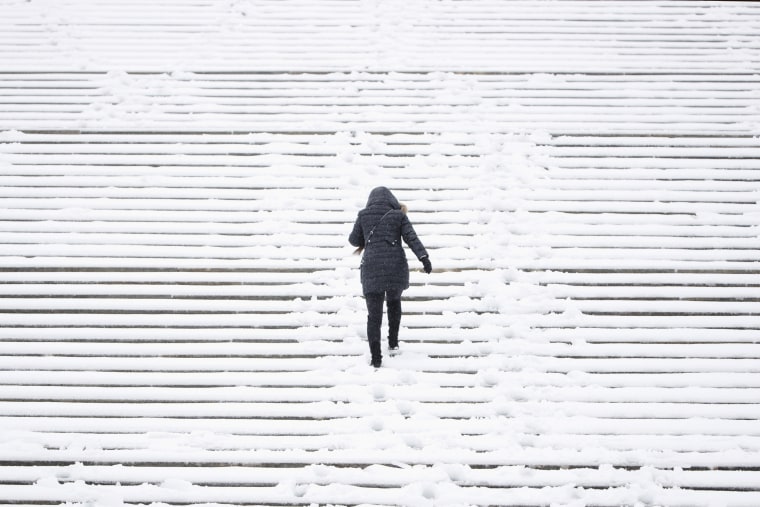 Image: A woman climbs the snow covered steps of the Philadelphia Museum of Art