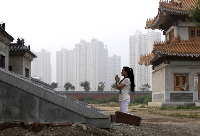 Image: A woman prays in Tianjin