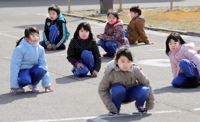 Image: Elementary school students crouch during an evacuation drill