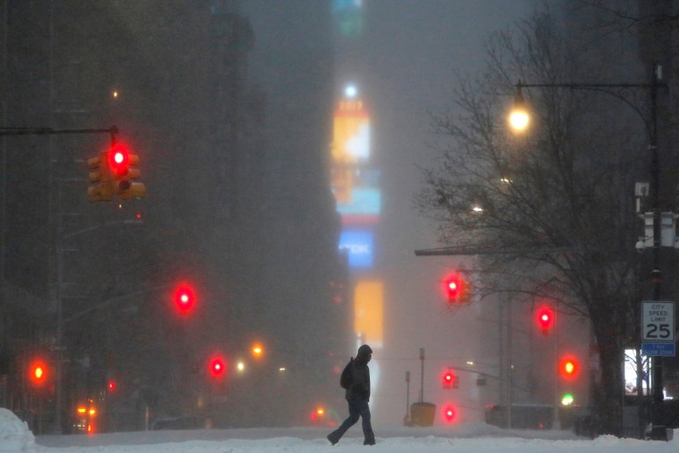 Image: Times Square is seen in the background as a man walks along West 59th street in falling snow in Manhattan, New York