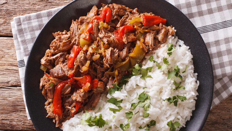 Cuban cuisine: ropa vieja meat with rice garnish on a plate  close-up. Horizontal view from above