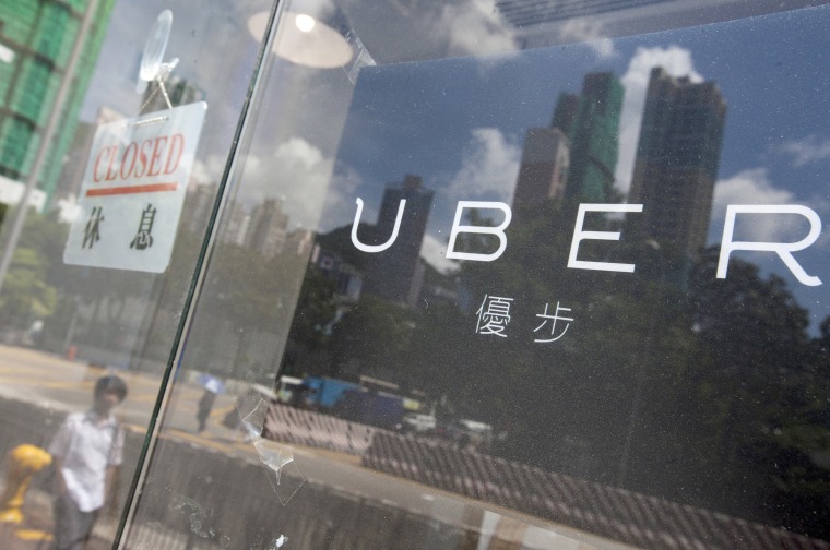 Image: Buildings are reflected in a window of an office of the taxi mobile app service Uber.