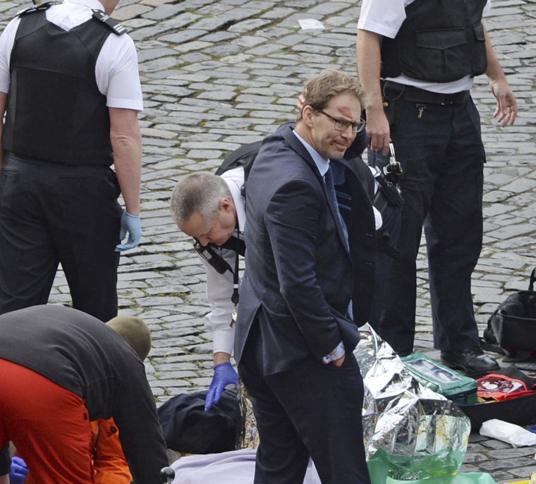 Conservative MP Tobias Ellwood stands among the emergency services personnel at the scene of an attack outside the Palace of Westminster on March 22.