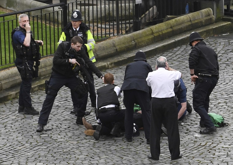A police officer points a gun at a man on the ground outside the Palace of Westminster on Wednesday.