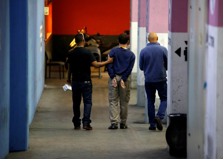 U.S.-Israeli teen arrested in Israel on suspicion of making bomb threats against Jewish community centres in the United States, Australia and New Zealand is escorted by security personnel following his hearing at Magistrate's Court in Rishon Lezion