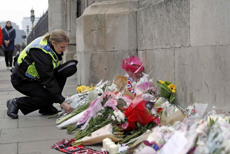 Image: A police officer lays a floral tribute near Westminster Bridge following a recent attack in Westminster, in London
