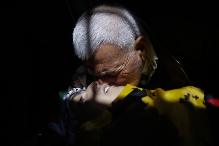 Image: A relative kisses the body of a 17-year old Palestinian Mahmoud Hattab during his funeral at the Jalazoun refugee camp near the West Bank city of Ramallah