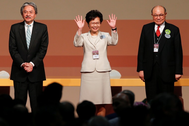 Image: Carrie Lam waves after she won the election for Hong Kong's next Chief Executive as other candidates John Tsang and Woo Kwok-hing stand next to her in Hong Kong