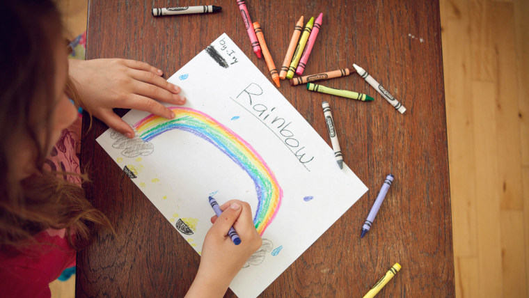 girl drawing rainbow with crayons