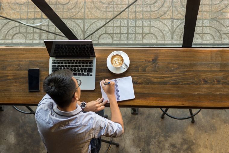 Image: A man sits at a table in a coffee shop