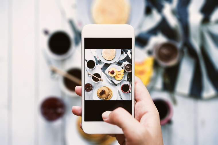 Image: Person taking picture of breakfast spread.