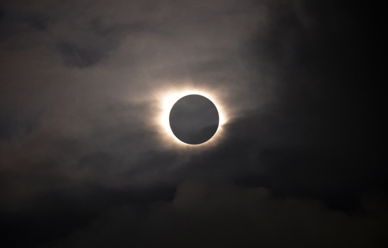 Image: A total solar eclipse is visible through the clouds as seen from Vagar on the Faeroe Islands, Friday, March 20, 2015.