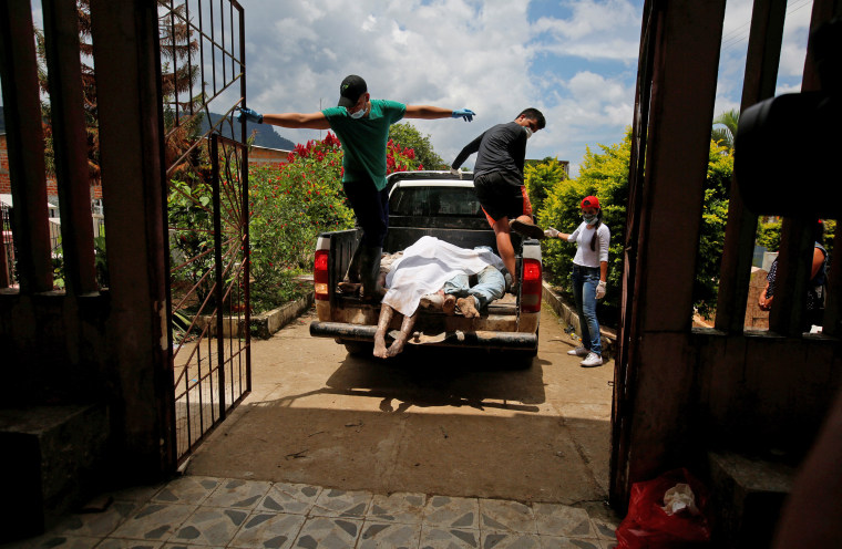 Men arrive in a vehicle with bodies to be identified after flooding and mudslides caused by heavy rains in Villagarzon