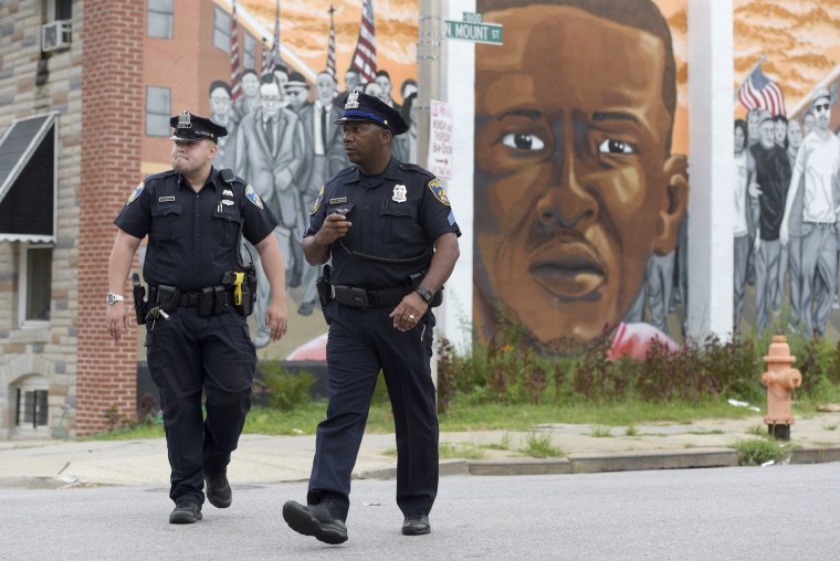 Image: Baltimore police walk near a mural depicting Freddie Gray