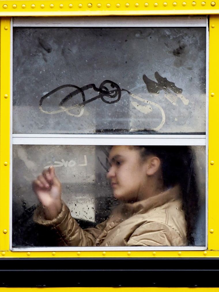 Image: A girl draws with the condensation on a school bus window