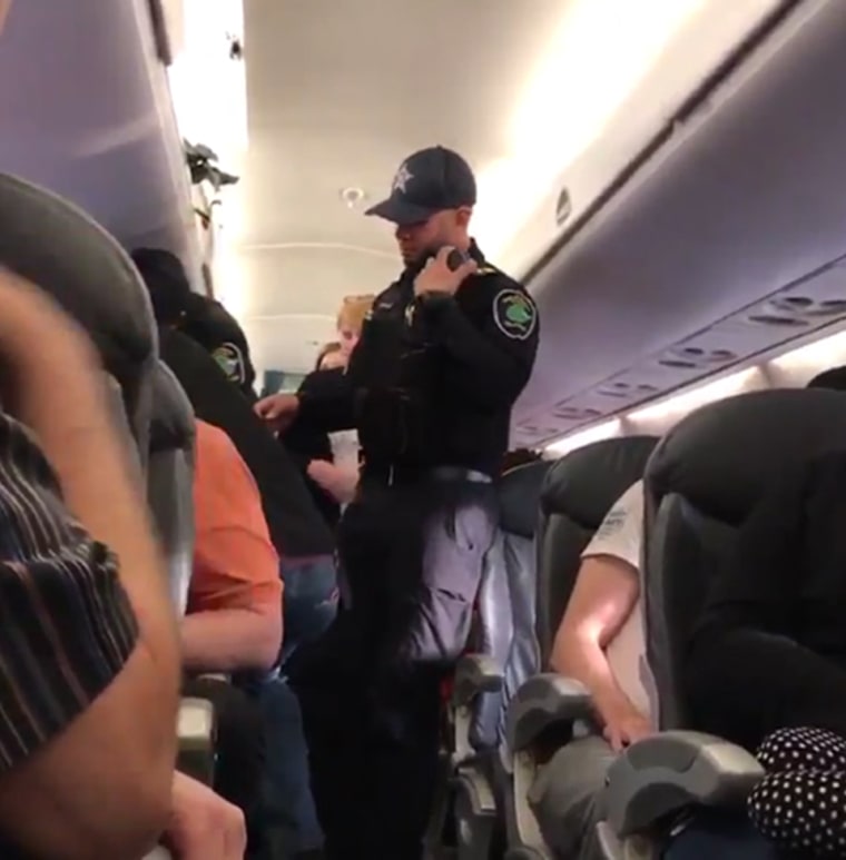 Image: Security stand in the aisle before forcibly removing a United Airlines passenger from a plane