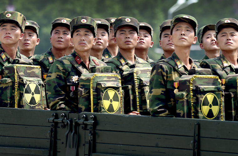 Image: North Korean soldiers turn and look towards leader Kim Jong Un as they carry packs marked with the nuclear symbol
