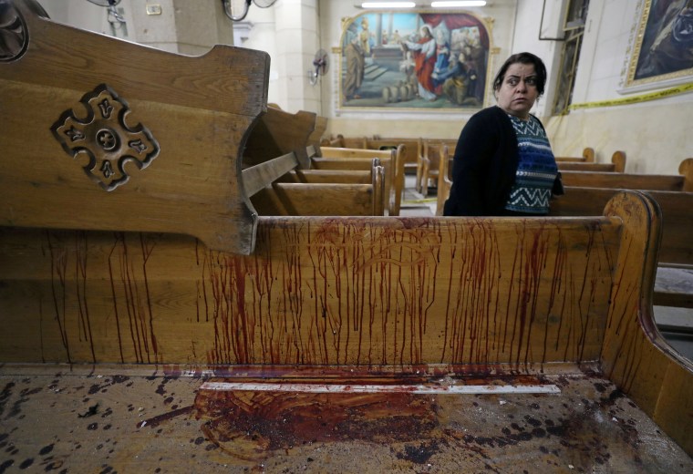 Image: A woman stands near a pew covered in blood inside a Coptic church that was bombed on Sunday in Tanta