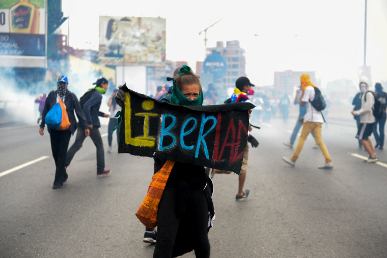Image: A woman holds a sign stating Libertad during the opposition clash with riot police in Venezuela