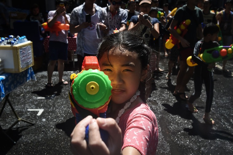 Image: A girl aims a water pistol at the camera during Songkran