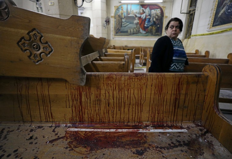 Image: A woman stands near a pew covered in blood inside a Coptic church that was bombed on Sunday in Tanta
